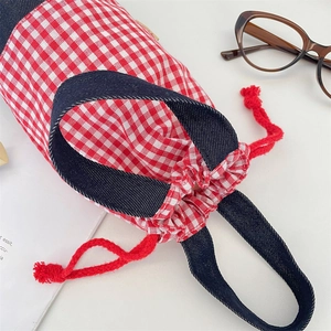 Close-up of red plaid drawstring water bottle bag with navy blue handles and rope