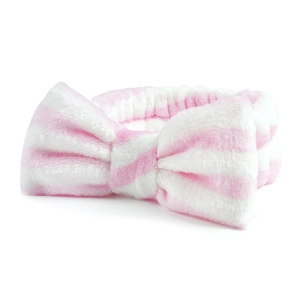 Macro-opname van roze en wit gestreepte pluche hoofdband met zachte strik voor gezicht