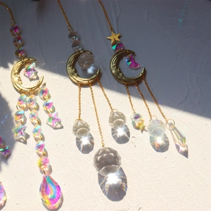 Detailed view of sun and moon crystal suncatchers casting rainbow light on a white surface