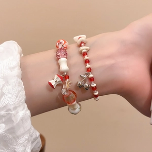 Detail of beaded bracelets with apple and cherry pendants worn on a woman wrist