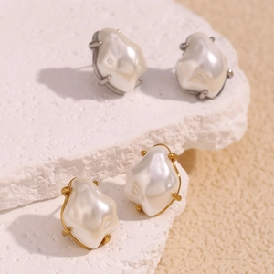 Macro view of gold and silver baroque pearl earrings on a natural white stone texture