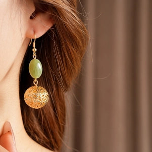 Detail of vintage resin hoop earring with green jade bead and hollow gold metal sphere