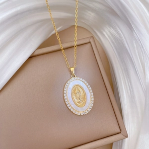 Macro shot of gold oval pendant with Virgin Mary relief and cubic zirconia on silk