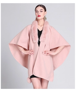 Close-up of elegant pink knit poncho with plush faux fur collar and pom-pom details