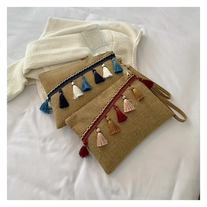 Detail of bohemian straw woven clutches featuring colorful tassels and texture on white fabric