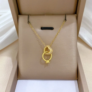 Dettaglio della collana con cuore e anello intrecciati dorati e cristalli viola in scatola