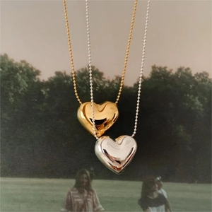 Polished heart pendant necklace in gold and silver finish on a nature background
