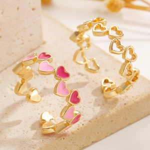 Dettaglio macro di anello a cuore dorato con smalto rosa e rosso su base in pietra