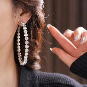 Close-up of a silver large hoop earring with clear rhinestones on a female model