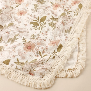 Close-up of cotton floral baby blanket showing vintage print and tassel edge details
