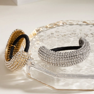 Close-up of gold and silver rhinestone ponytail holders on water ripple glass