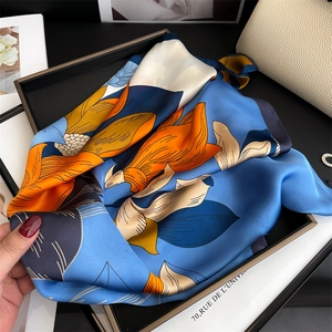 Detail showing vivid orange and blue floral pattern on smooth silk-like neck scarf