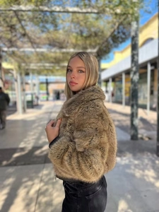 Nahaufnahme der braunen Kunstpelzjacke mit schwarzem Rippbündchen und Reißverschluss
