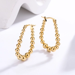 Detailed view of golden beaded hoop earrings with a teardrop shape and polished finish
