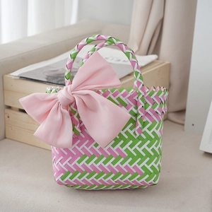 Detailed view of woven basket bag with pink bow, showing high-quality texture and color mix