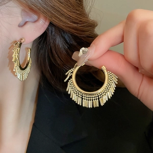 Detail of gold circular fringe earrings featuring metallic bars with a polished finish