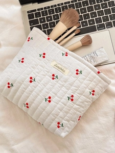 Quilted cherry print cotton toiletry bag for makeup storage on a soft neutral background