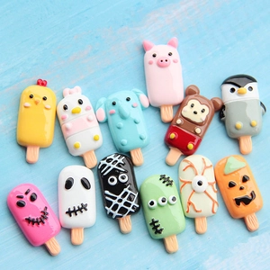 Flat lay of colorful resin popsicle charms with cartoon animal and Halloween themes