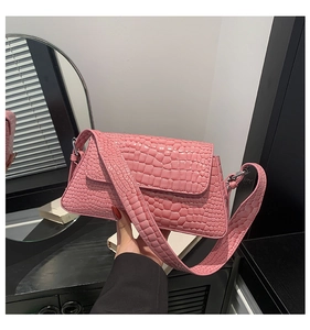 Detail shot of a pink crocodile texture handbag showing a glossy finish and wide strap