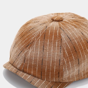 Gros plan d'une casquette gavroche marron montrant la texture du tissu rayé rétro