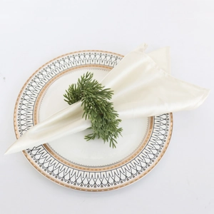 Close-up of pine needle napkin ring on a ceramic plate with beige fabric napkin