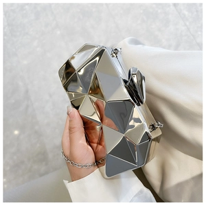 Detail of silver geometric faceted evening clutch with metallic surface and chain strap