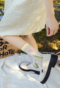 Close-up of white mesh socks with pink tulips and wavy edges worn with Mary Jane shoes