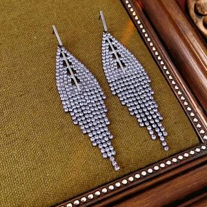 Close-up of silver tassel earrings with purple rhinestones on green fabric