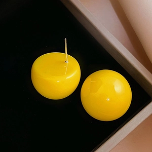 Macro shot of bright yellow round acrylic stud earrings on a sleek black background