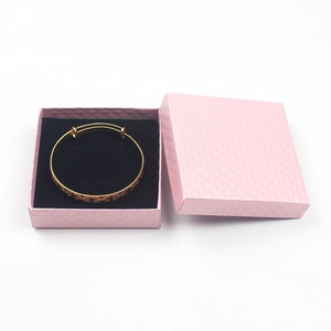 Detail view of a gold floral engraved bracelet inside a pink square jewelry gift box