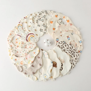 Flat lay of multiple colorful cotton baby bibs with cute cartoon prints in a circle