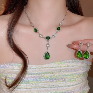 Primo piano dell'elegante ciondolo a goccia verde smeraldo e orecchini abbinati sulla modella