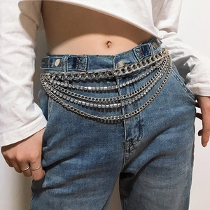 Détail de chaînes de taille argentées multicouches avec strass brillants sur un jean