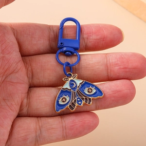Exquisite moth keychain with blue enamel moon patterns and gold metal frame on a hook