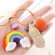 Detail of handmade crochet keychain featuring rainbow cloud and persimmon charms