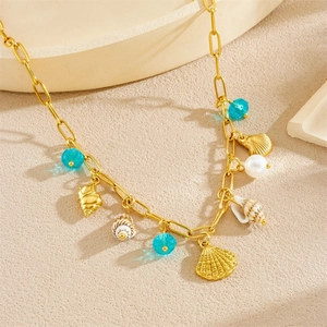 Gold chain necklace with scallop, conch shell pendants, blue beads and pearls on beige surface