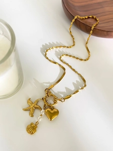 Detail of gold starfish and shell charms with white pearls on a unique mixed chain necklace