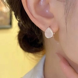 Close-up of pink teardrop earrings featuring translucent stones with silver metal claw settings