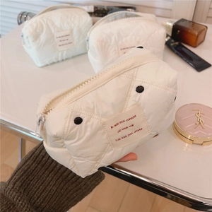 Détail de la texture matelassée de la trousse de maquillage crème à pois noirs