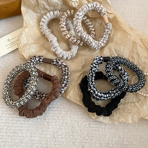 Close-up of a diverse set of fabric woven hair scrunchies with pearls and leopard patterns