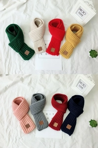 Close-up of thick knit scarves in various colors with a brown faux leather label detail