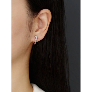 Macro detail of S925 sterling silver snake earrings with red gemstone eyes and clear stones
