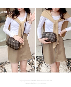 Detailed view of brown checkered crossbody bag with gold logo and slim shoulder strap