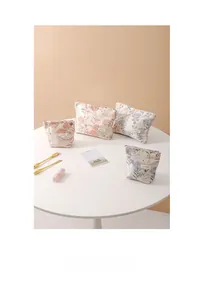Floral cotton makeup bags in various sizes displayed on a white table with cosmetics