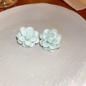 Detailed view of mint green floral earrings with multi-layered petals on a ceramic tray