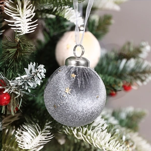 Silver velvet Christmas ball with gold star glitter on snow-dusted green pine branch