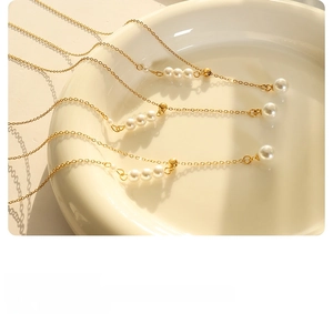 Detailed view of elegant gold-toned pearl necklaces laid on a minimalist white ceramic plate