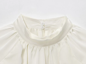 Detail of white blouse featuring a chic stand collar with delicate pleated edges