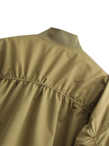 Detail view of olive green bomber jacket featuring pleated back seams and ribbed neckline