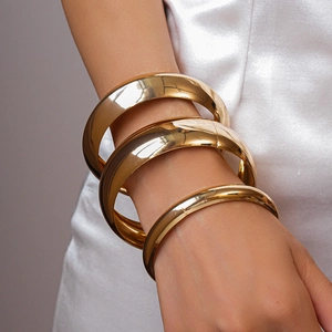 Close-up of three-piece set of high-gloss gold metallic geometric bangle bracelets